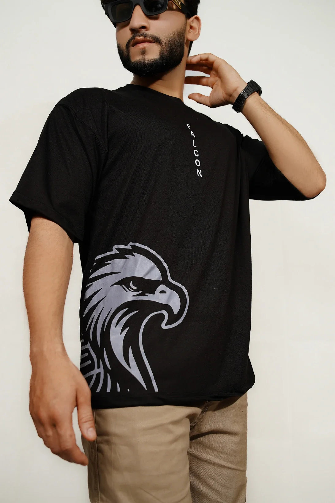 Close-up of Model wearing black Falcon oversized drop-shoulder t-shirt with minimalist front insignia